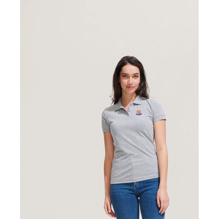 Mujer con polo gris de manga corta con logo naranja y azul, combinado con vaqueros azules.