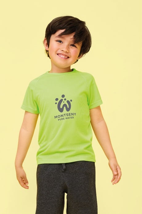 Niño con camiseta verde claro de manga corta con logo Montseny Pure Water y pantalones cortos oscuros.