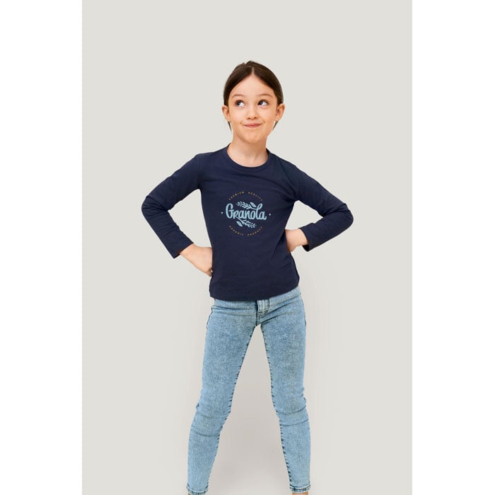 Niña con camiseta azul marino de manga larga con logo Granola y pantalones vaqueros ajustados claros.