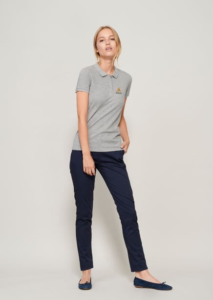 Mujer con polo gris de manga corta con logo naranja y pantalones azul marino ajustados.