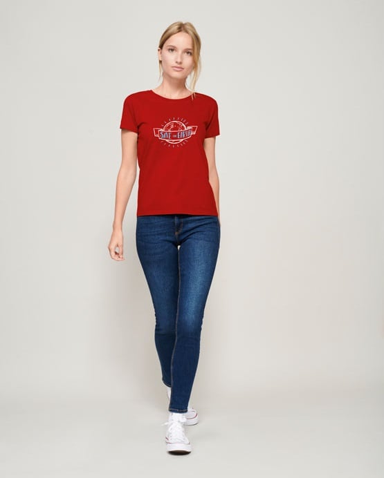 Camiseta roja de manga corta con estampado blanco y azul combinada con vaqueros ajustados y zapatillas blancas.