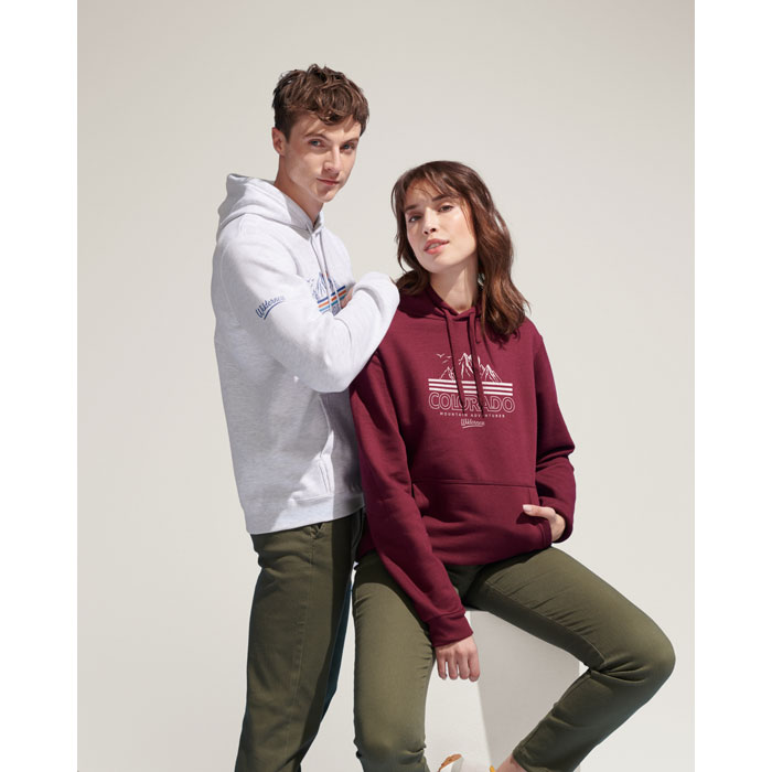 Hombre con sudadera blanca con capucha y mujer con sudadera burdeos con capucha y estampado Colorado, ambos con pantalones verdes.