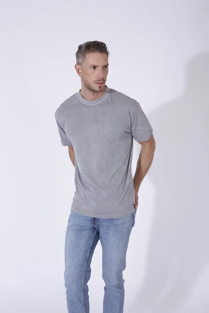 Hombre con camiseta gris de algodón y vaqueros azul claro.