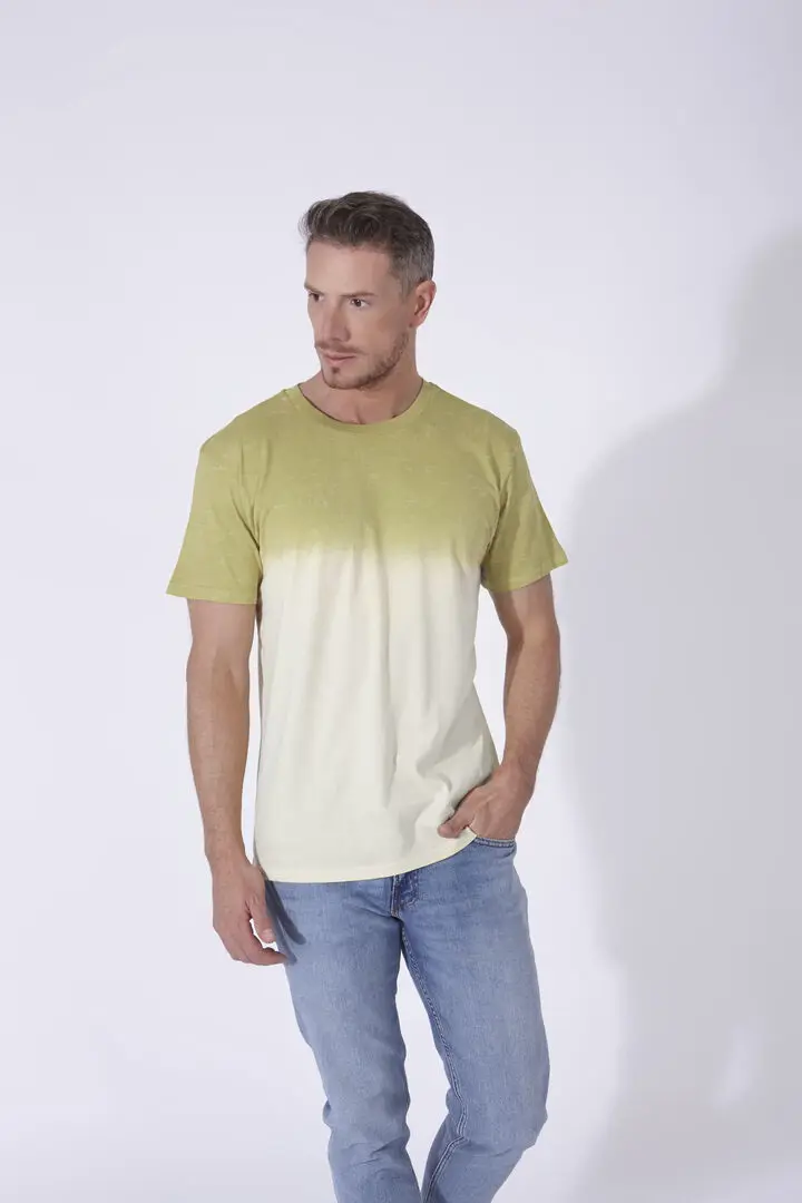 Hombre con camiseta de manga corta degradada en tonos verde y beige combinada con vaqueros azul claro.