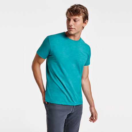 Hombre con camiseta de manga corta azul turquesa y pantalones grises.