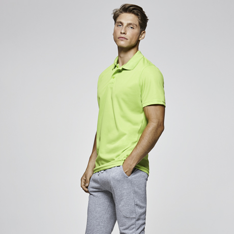 Hombre con polo verde lima de manga corta y pantalones deportivos grises.