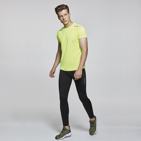 Hombre con camiseta deportiva amarilla y malla negra ajustada con zapatillas verdes.