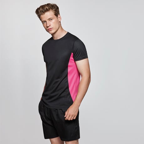 Hombre con camiseta deportiva negra con detalles rosa y pantalones cortos negros.