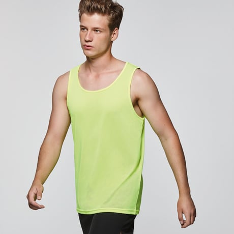 Hombre joven con camiseta sin mangas amarilla fluorescente y pantalones deportivos negros.