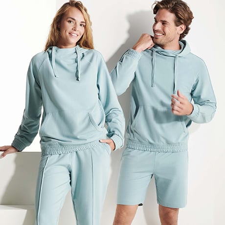 Pareja con sudaderas y pantalones deportivos de color azul claro, ella con pantalón largo y él con pantalón corto.