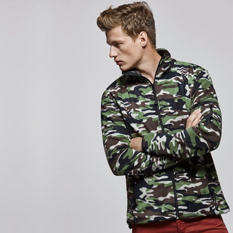 Hombre con chaqueta polar de camuflaje verde, marrón y negro con cremallera y cuello alto.