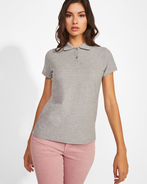 Mujer con polo gris de manga corta y pantalones rosa claro.