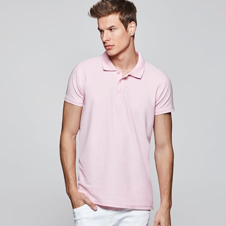 Hombre con polo rosa de manga corta y pantalón blanco.