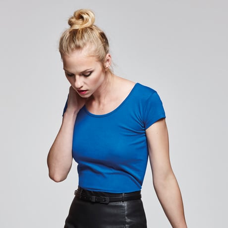 Mujer con camiseta azul de manga corta y falda negra de cuero con cinturón.