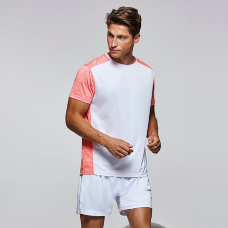 Hombre con camiseta técnica blanca y coral y pantalones cortos blancos para deporte.