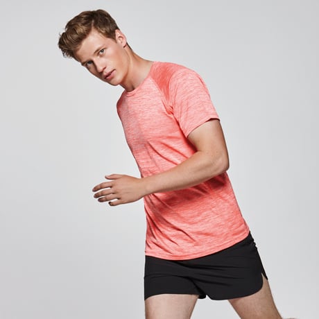 Hombre con camiseta técnica naranja y pantalones cortos negros en posición de carrera.