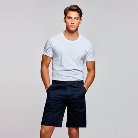 Hombre con camiseta blanca de manga corta y pantalones cortos azul marino.