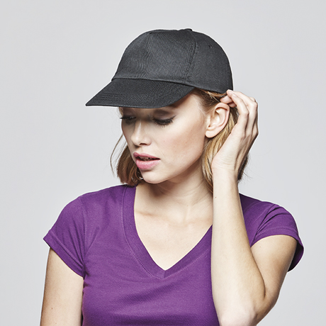 Mujer con camiseta morada y gorra negra ajustable de algodón.
