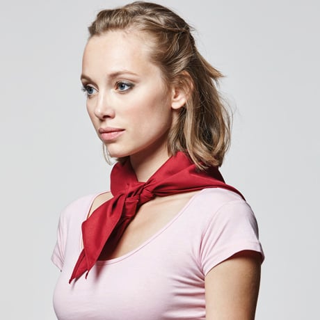 Mujer con pañuelo rojo anudado al cuello y camiseta rosa de manga corta.