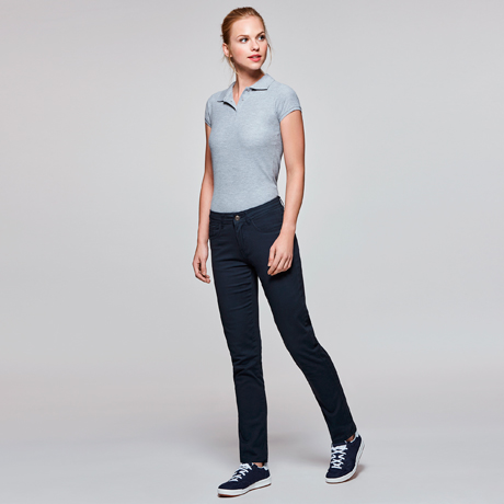 Mujer con polo gris de manga corta y pantalones negros ajustados con zapatillas deportivas azul marino.