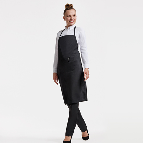 Mujer con delantal negro de algodón y camiseta blanca de manga larga.