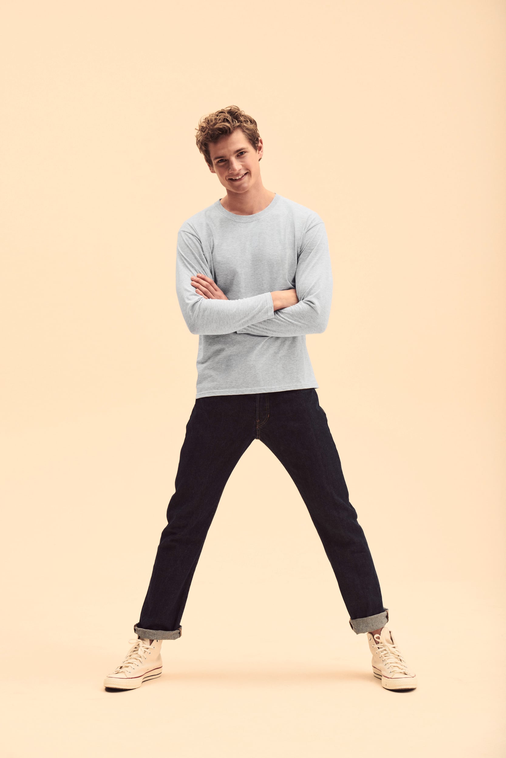 Hombre con camiseta gris de manga larga, vaqueros oscuros y zapatillas altas blancas.