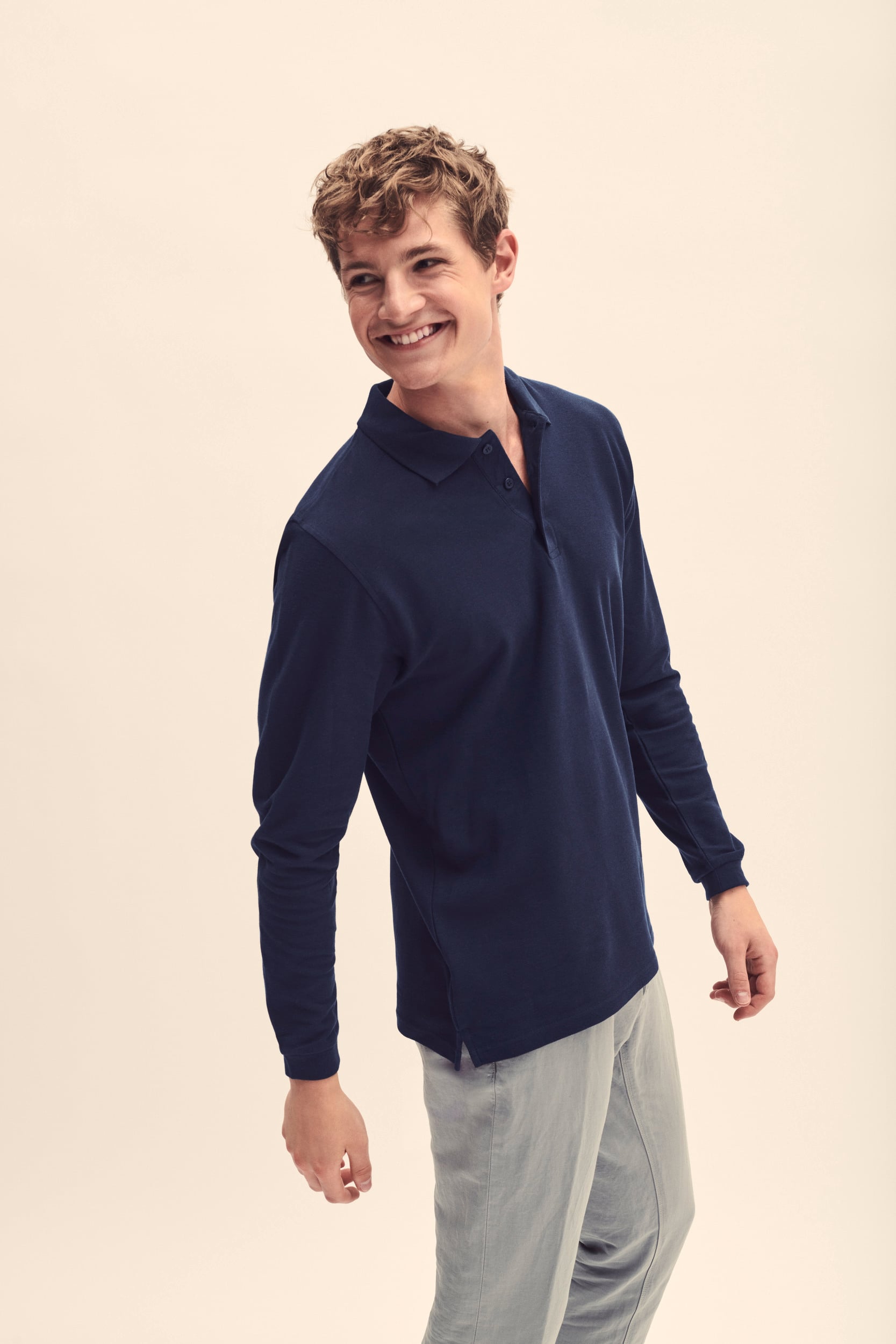 Hombre con polo azul marino de manga larga y pantalones claros.