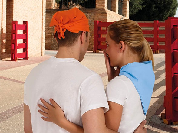 Pareja de espaldas con pañuelos naranja y azul y camisetas blancas en un entorno urbano.