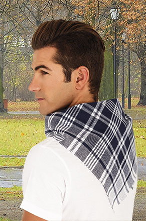 Hombre con pañuelo de cuadros en tonos grises y blancos sobre camiseta blanca en un parque.